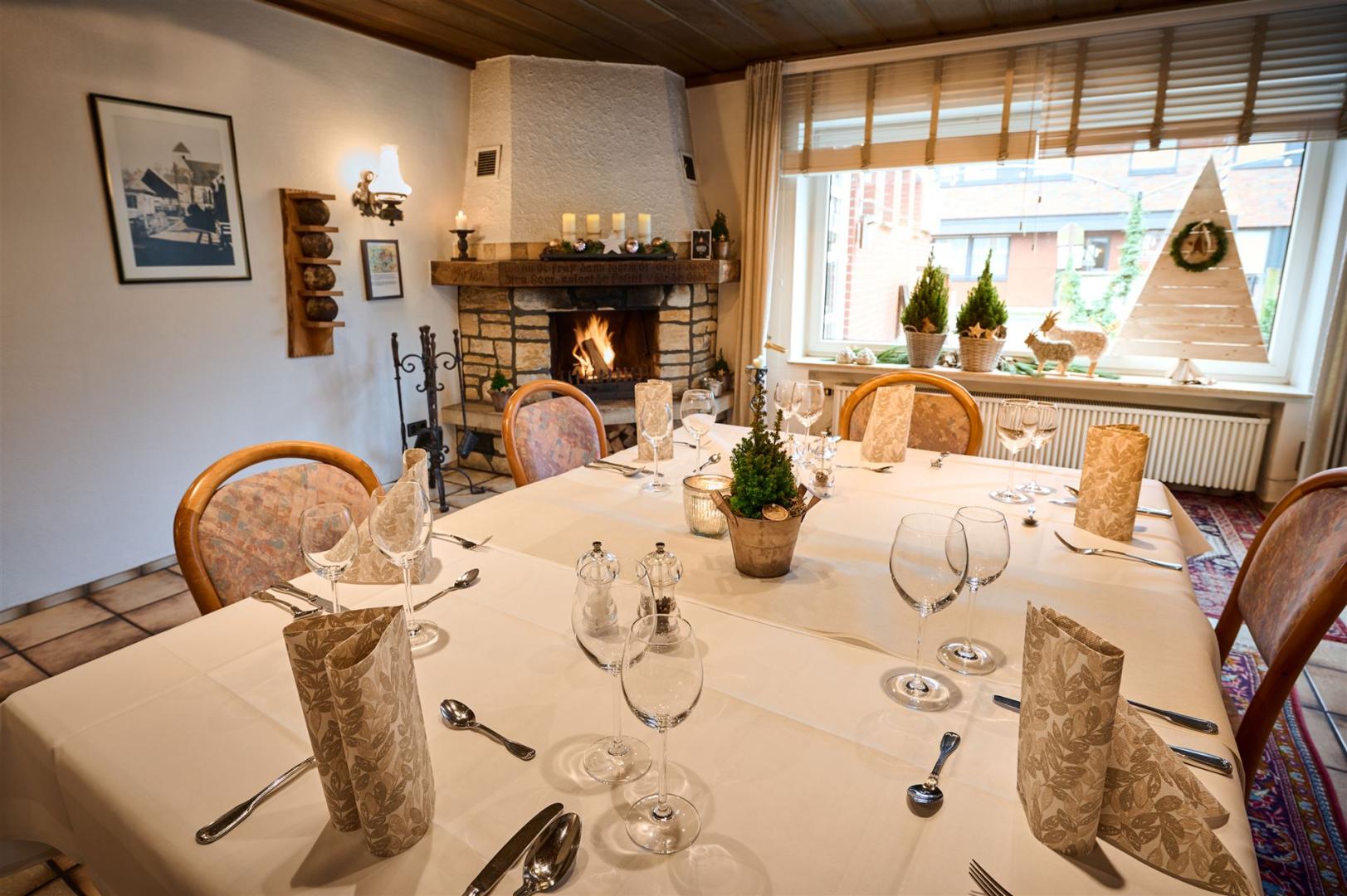 Foto van de clubkamer met gedekte tafel en brandende open haard