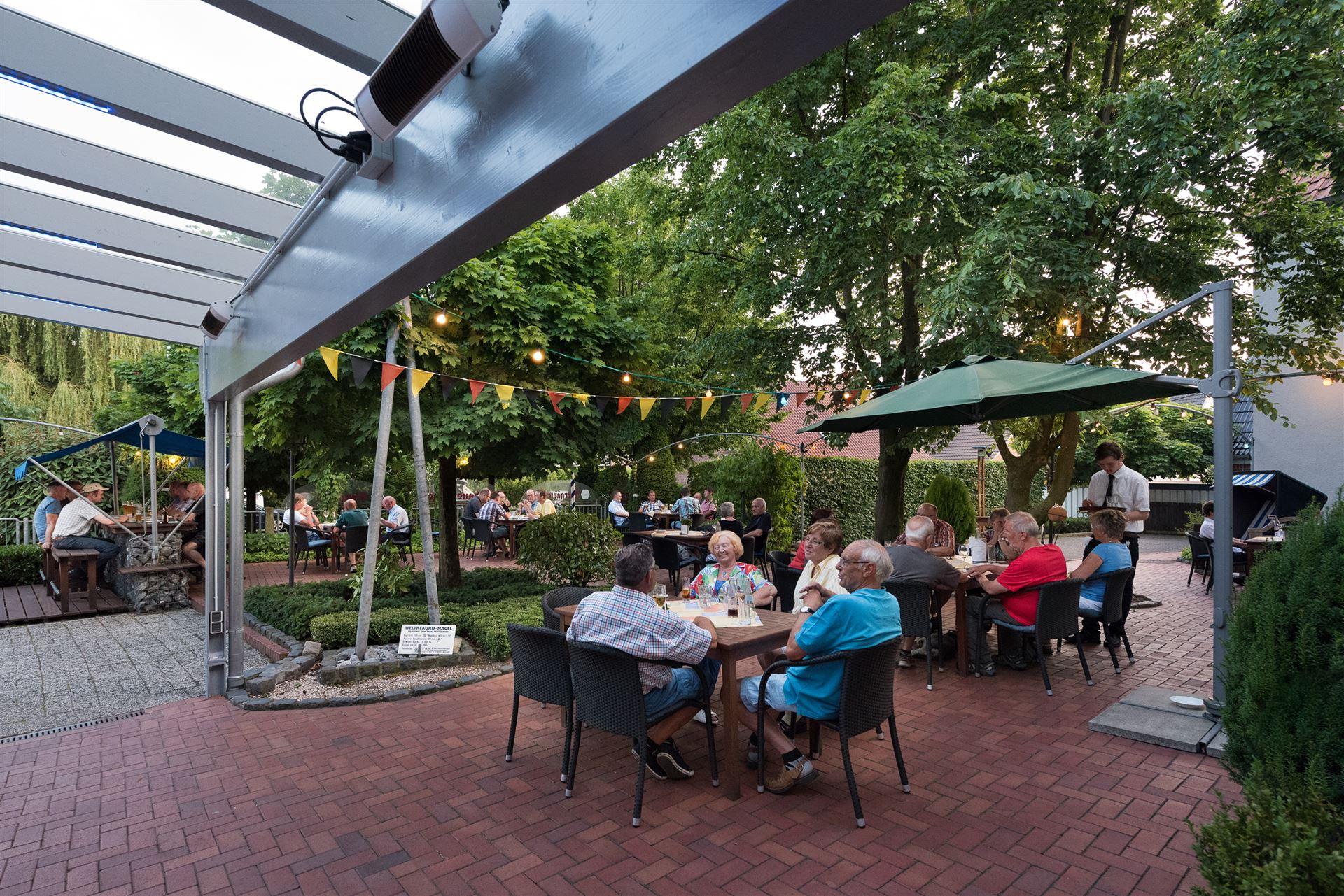 Foto toont de biergarten met gasten gefotografeerd vanuit de achteringang van het hotel