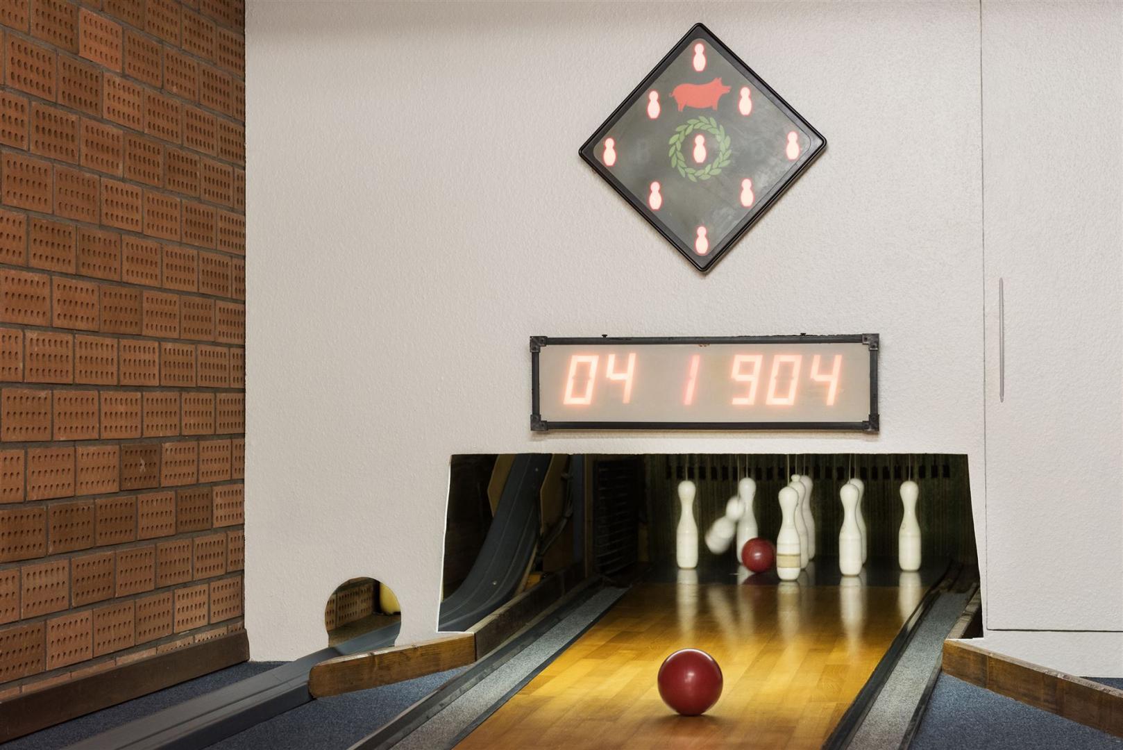 De afbeelding toont het einde van de kegelbaan met kegels en scorebord