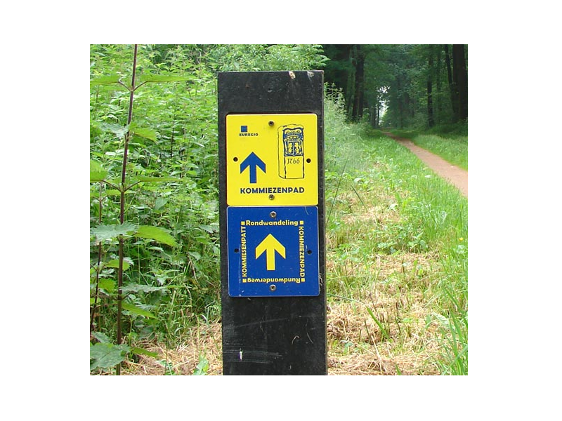 Wegbewijzering in blauw/geel in het bos voor het komiezenpad