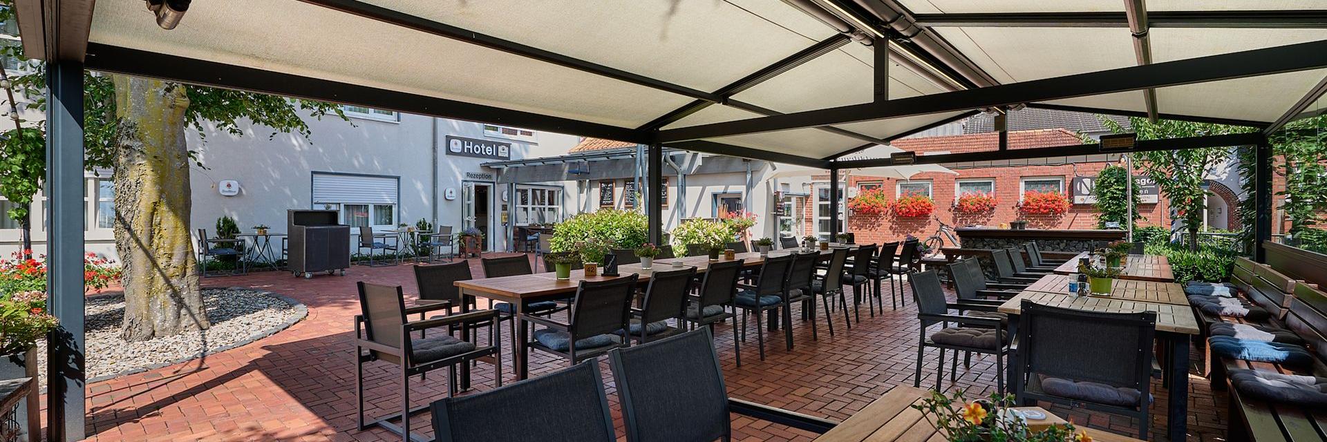Uitzicht op de biertuin vanuit het overdekte terras met op de achtergrond het hotel.