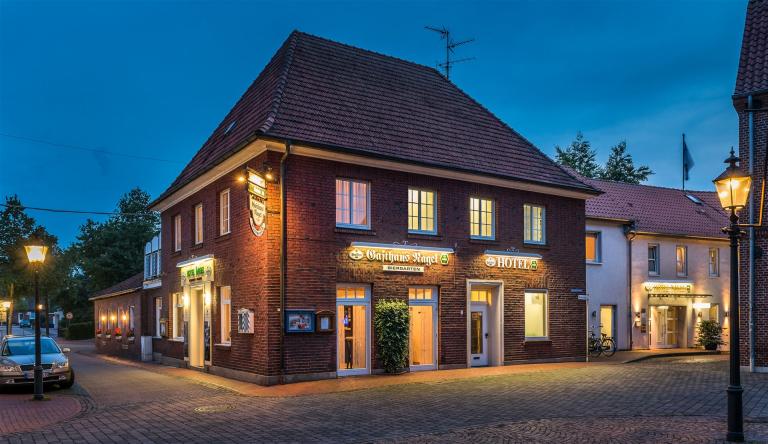 Buitenzicht van het hotel in de avond, gezien vanaf de kerk.