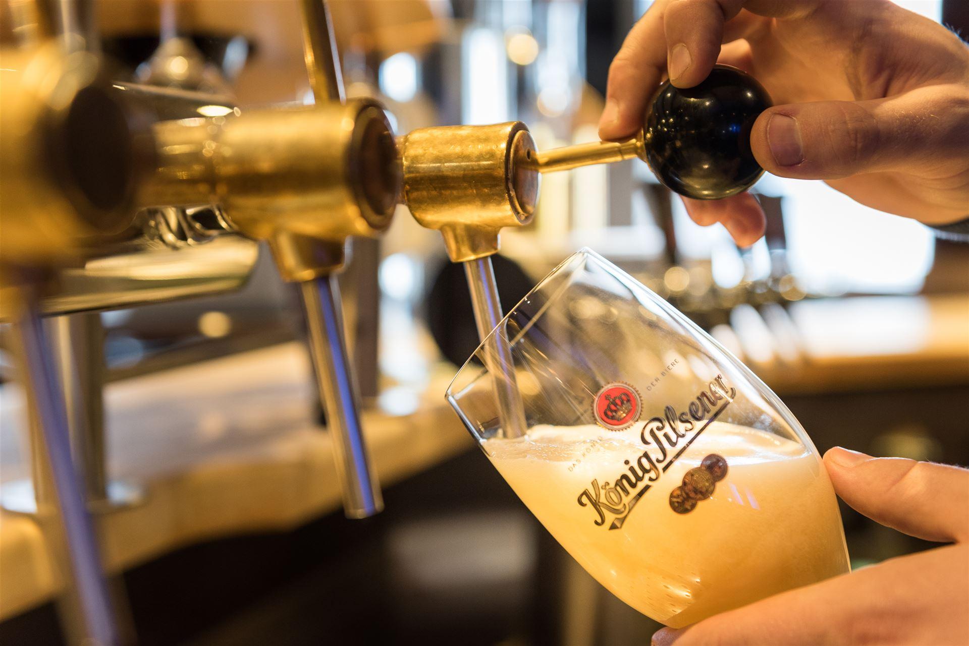 Close up van een "König Pilsener" glas aan de tap dat met bier wordt gevuld